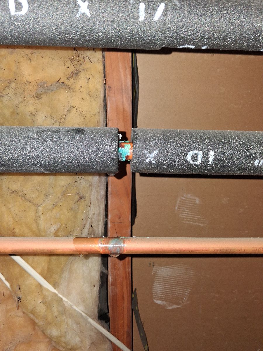 Exposed hot-water pipe with green corrosion at an open access area.